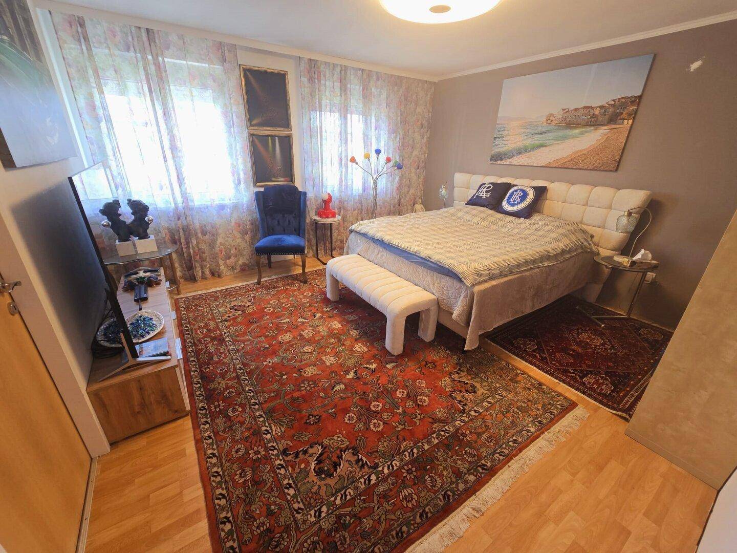 Gemütliches Schlafzimmer mit großem Bett, Teppich und Vorhängen, bietet eine entspannende Atmosphäre.