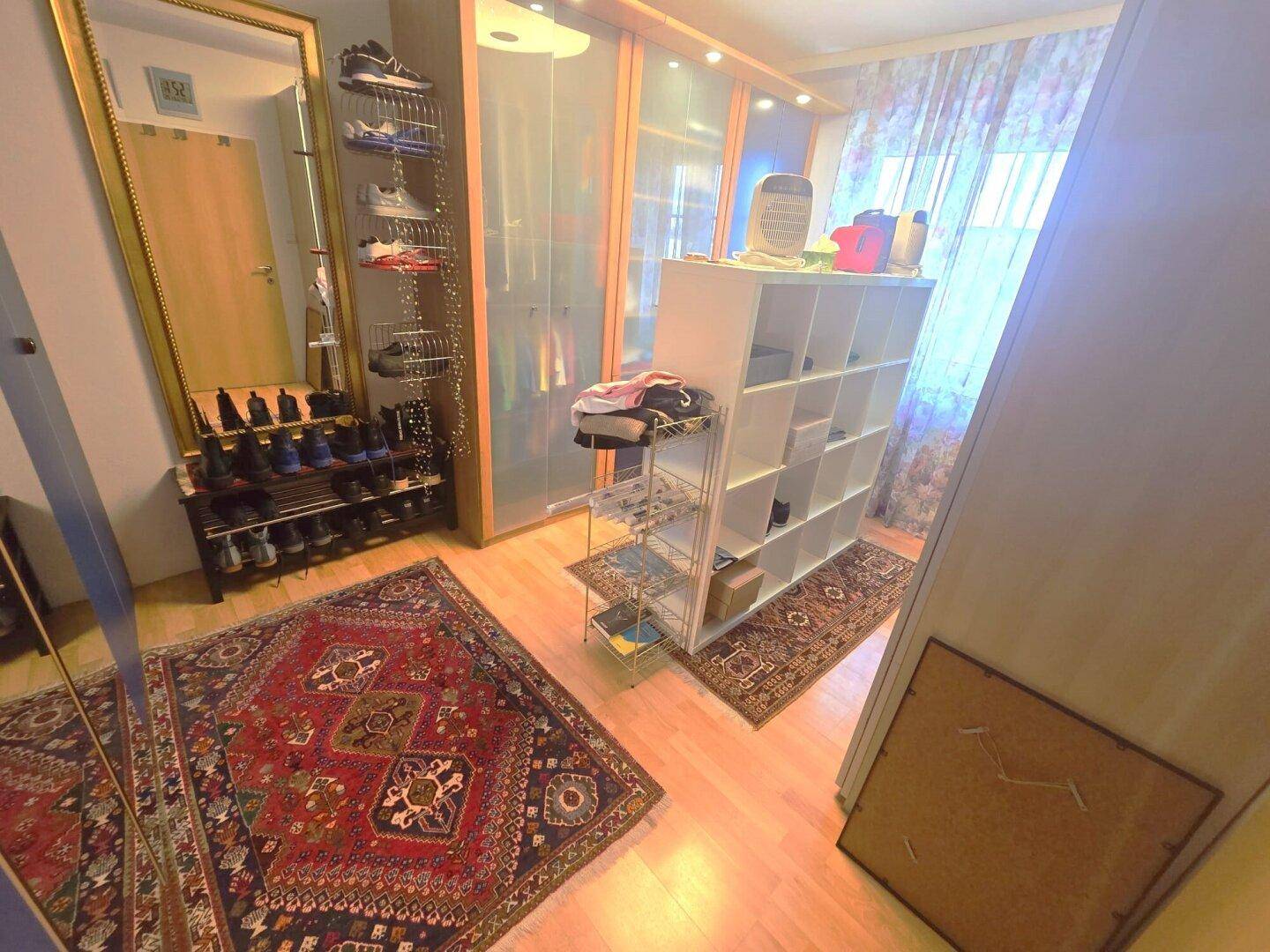 Geräumiger Ankleidebereich mit Kleiderschränken, Schuhregalen und großem Spiegel, bietet viel Stauraum.