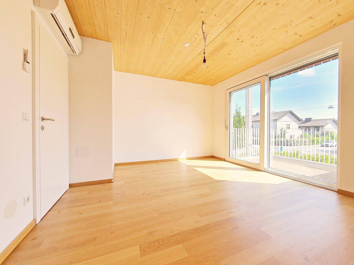 Geräumiges Schlafzimmer mit Holzbalkendecke, Parkettboden und Klimaanlage.