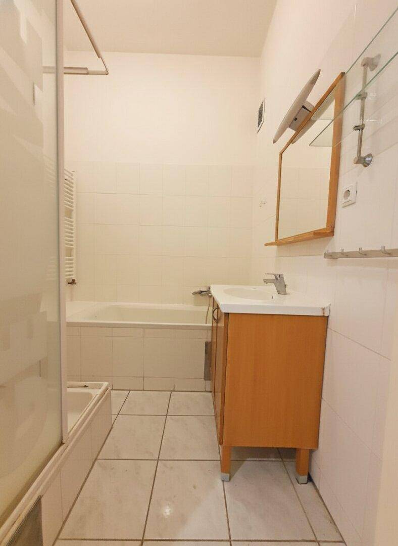 Badezimmer mit Badewanne, Duschabtrennung und Waschtisch, ausgestattet mit hellen Fliesen.