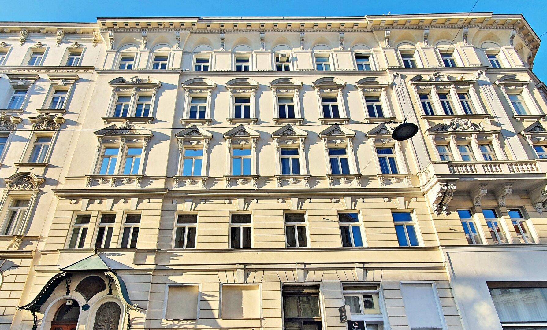Prächtige Altbaufassade mit vielen Fenstern und dekorativen Elementen, die den historischen Charakter des Gebäudes zeigt.
