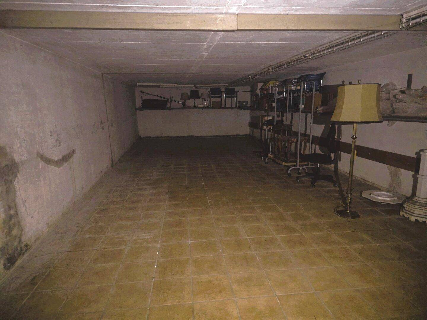 Geräumiger Kellerraum mit Fliesenboden und einfacher Einrichtung, ideal als Lager.