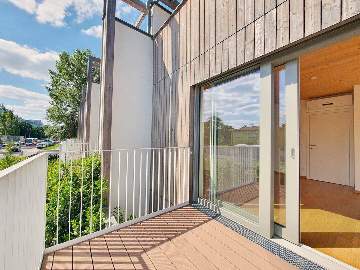 Balkon mit Holzverkleidung und Schiebetürzugang, bietet einen Blick auf die Umgebung.