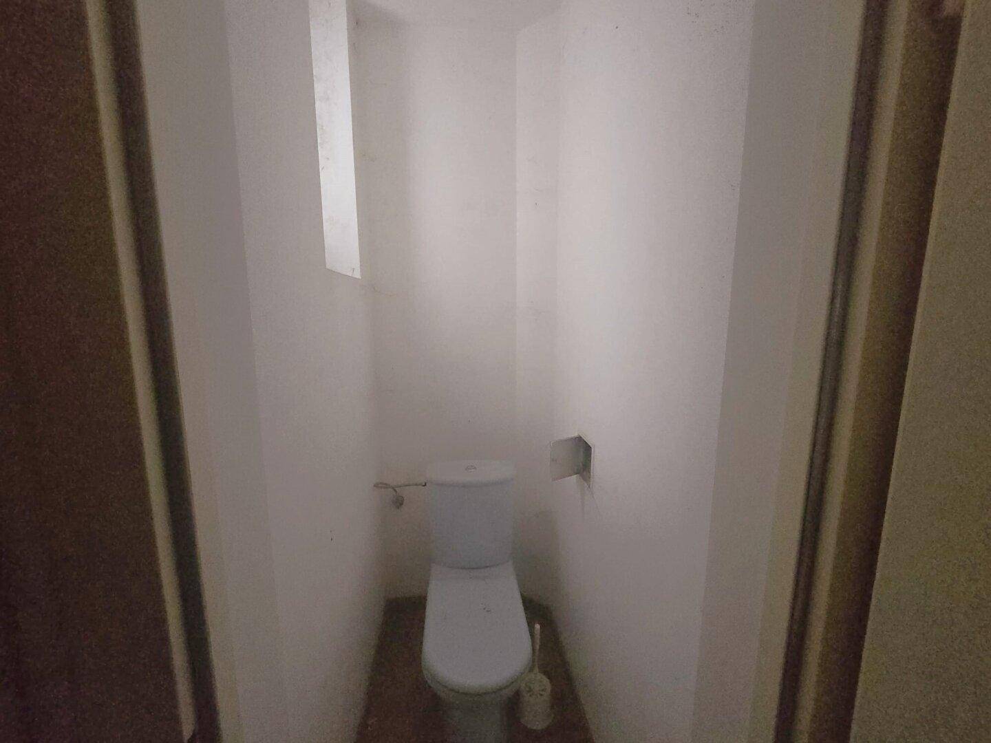 Kleines Gäste-WC mit einfacher Toilette und einem kleinen Fenster.