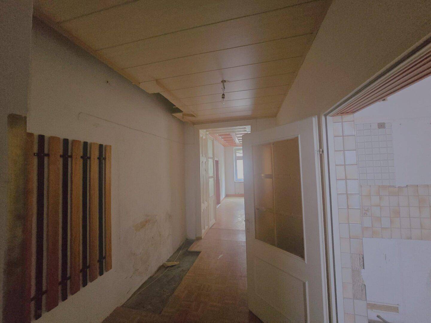 Langer Flur mit Holzdecke und alten Türen, der zu weiteren Räumen führt.
