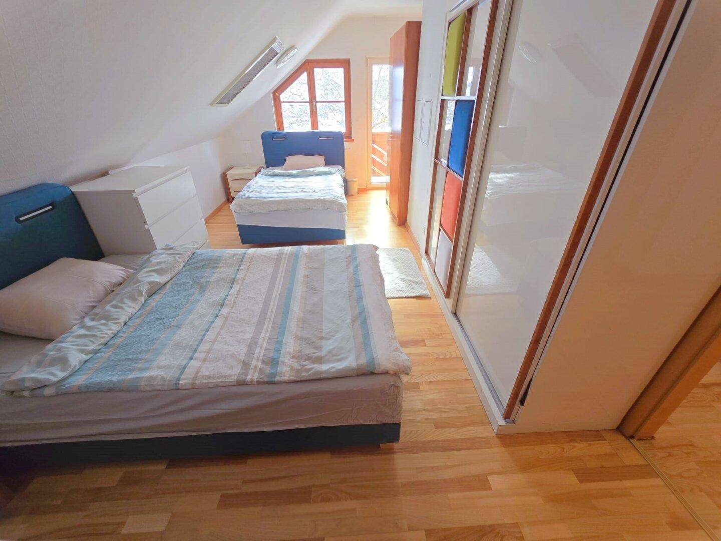 Schlafzimmer im Dachgeschoss mit Holzboden, Schiebetürenschrank und Dachfenster.