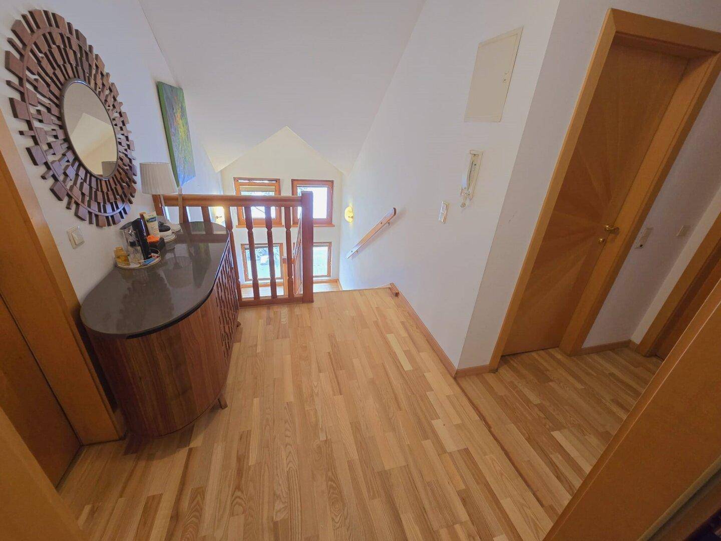 Heller Flur im Obergeschoss mit Holzboden und Blick auf die untere Etage.