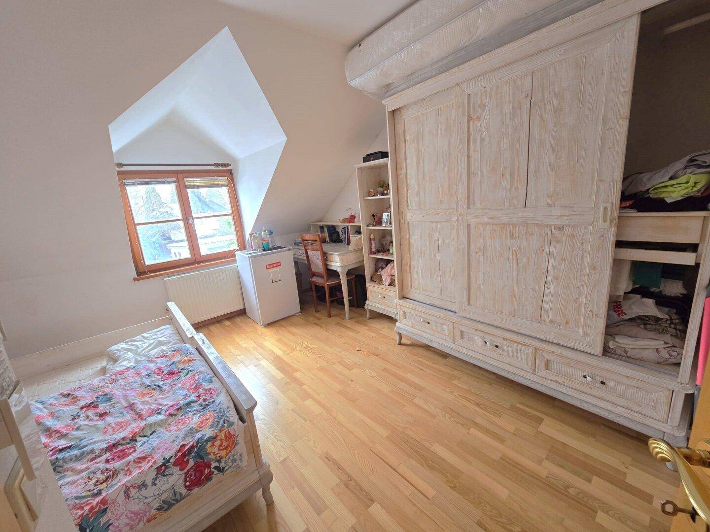 Schlafzimmer im Dachgeschoss mit Holzboden, großem Kleiderschrank und Dachfenster.