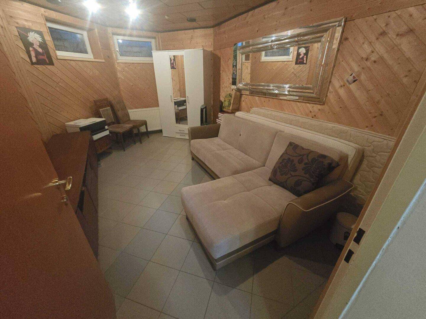 Gemütlicher Raum mit Holzvertäfelung, Sofa und großem Spiegel, ideal als Hobbyraum.