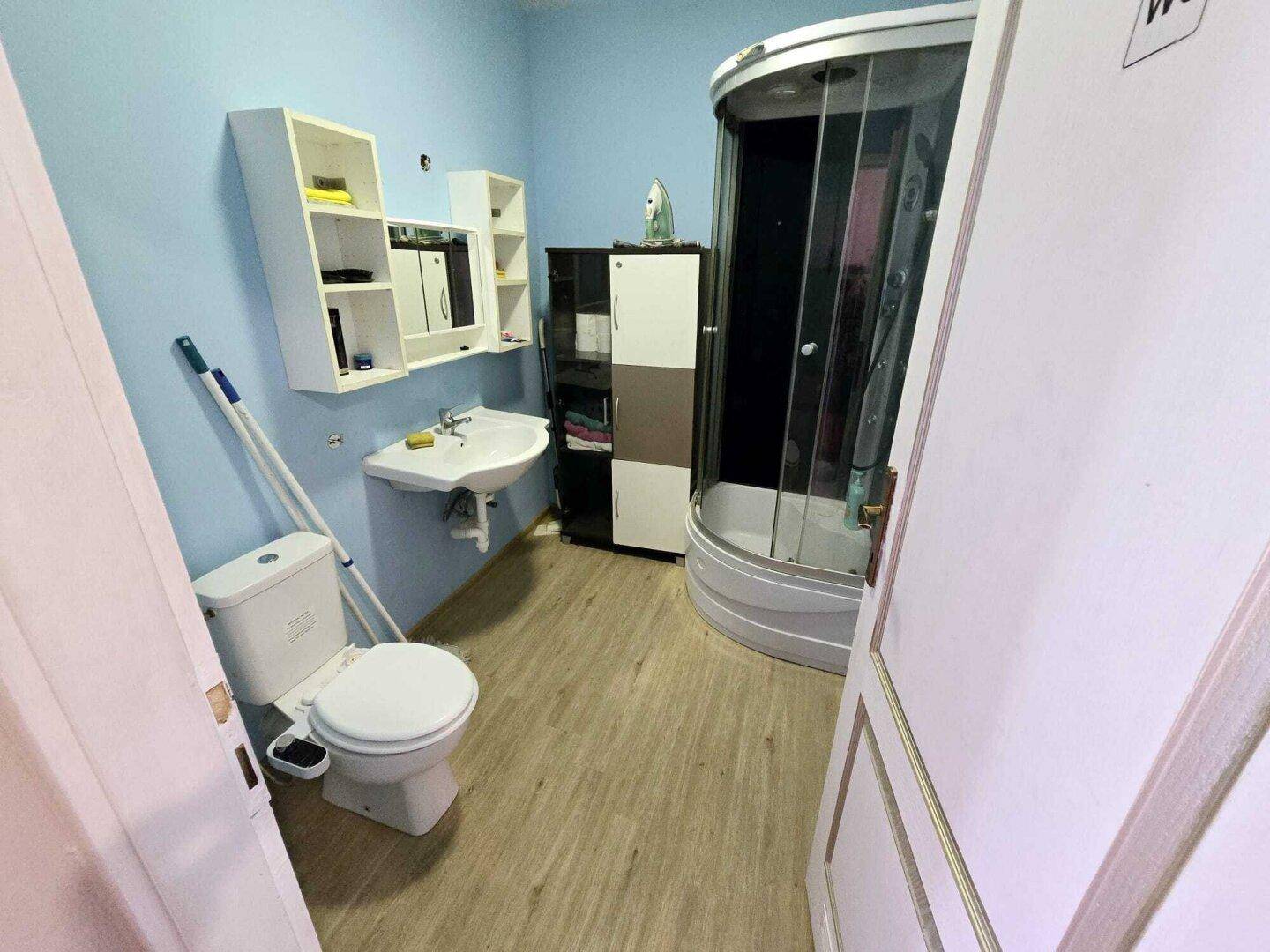 Badezimmer mit Duschkabine, Toilette, Waschbecken und hellblauen Wänden.