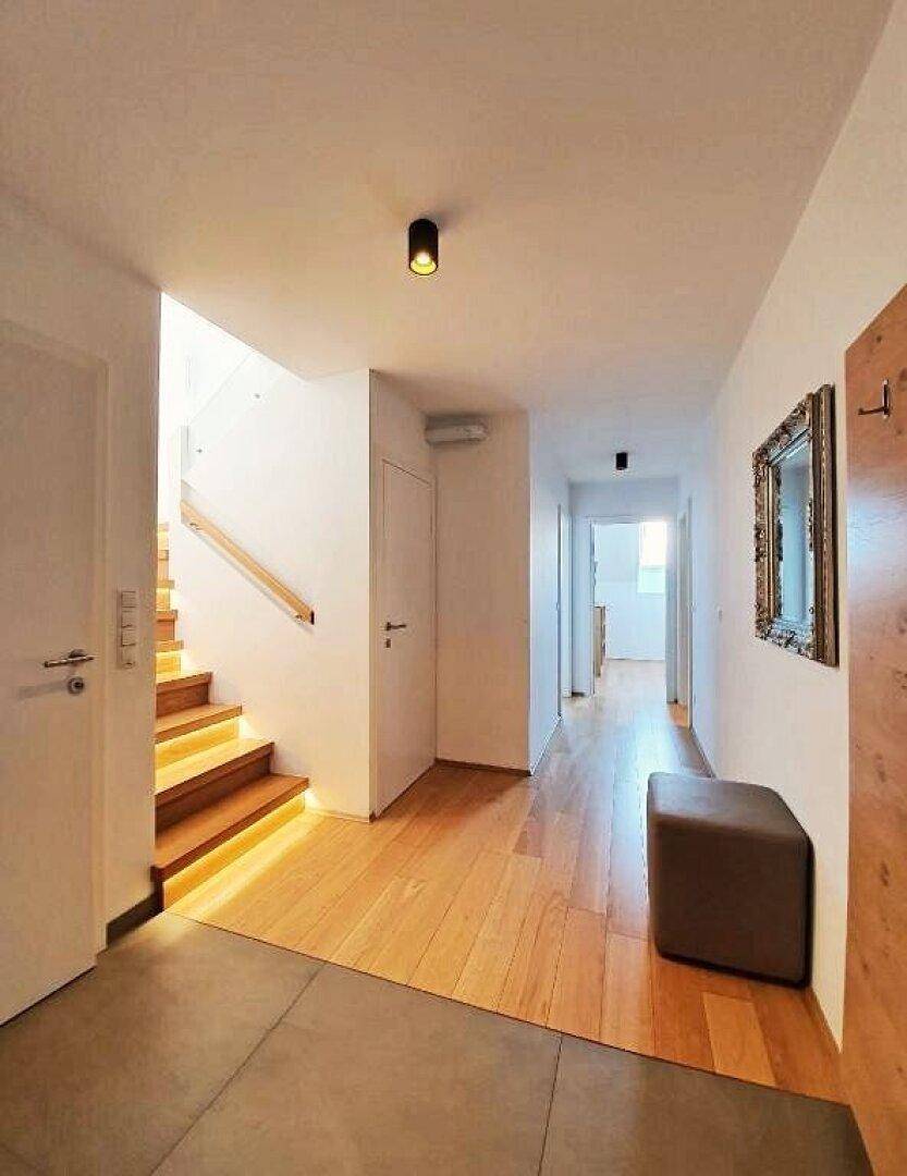 Geräumiger Flur mit Holzboden und Fliesenbereich, der zum Treppenhaus und weiteren Räumen führt.
