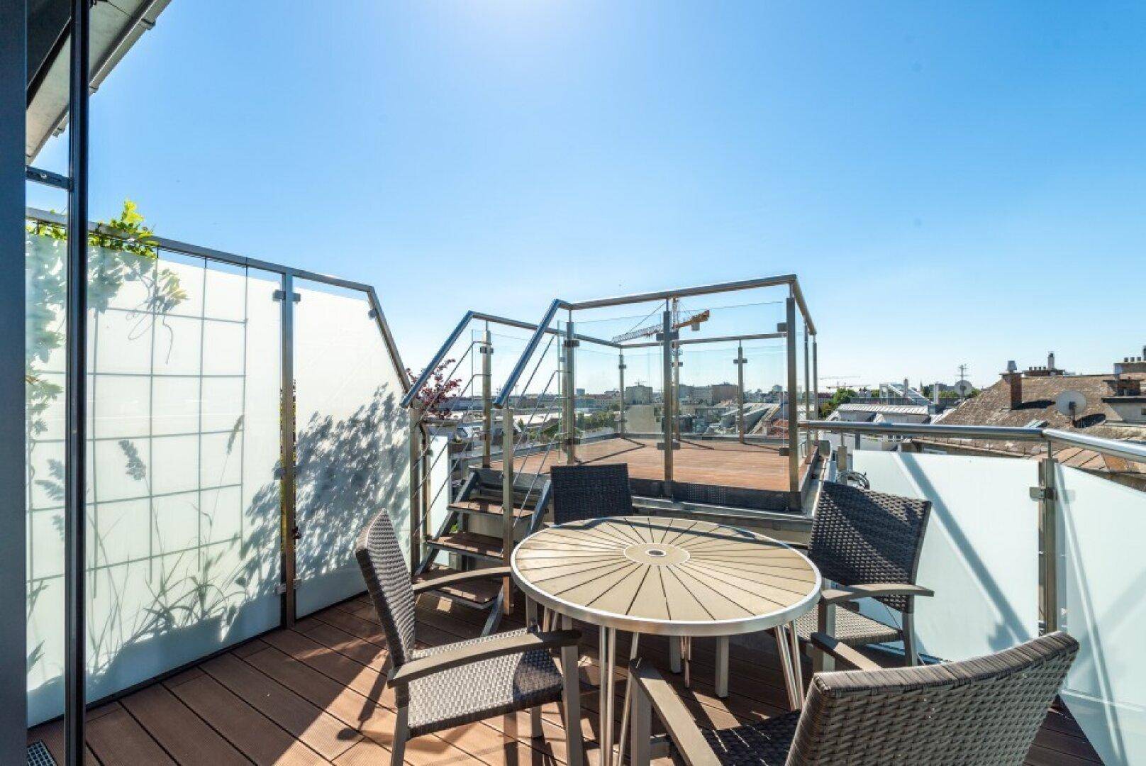 Geräumige Dachterrasse mit modernen Glasgeländern, Sitzgelegenheiten und weitem Blick über die Stadt.