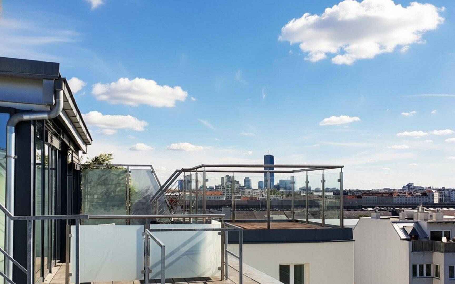 Weitläufige Dachterrasse mit Glasbrüstung und beeindruckendem Panoramablick auf die städtische Skyline.