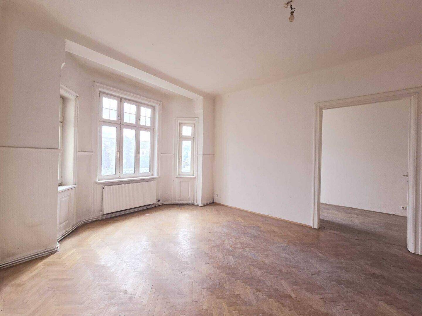 Lichtdurchflutetes Zimmer mit klassischem Fischgrätparkett und einem schönen Erkerbereich.