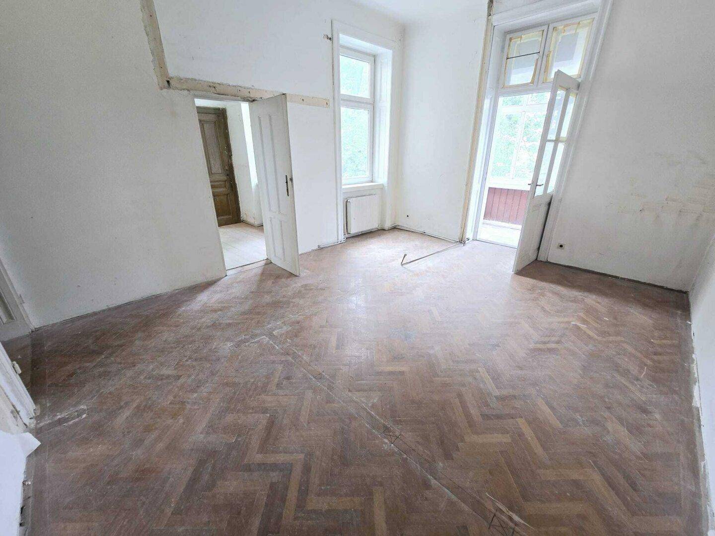 Helles Zimmer mit Fischgrätparkett und direktem Zugang zu einem sonnigen Wintergarten.