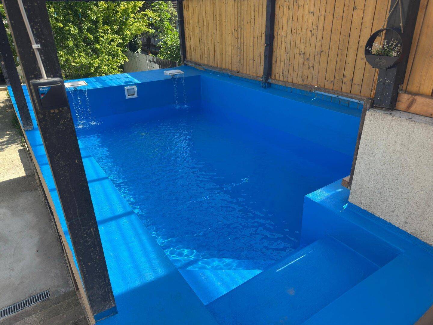 Detailansicht des erhöhten Pools mit leuchtend blauem Wasser und integrierten Stufen für einfachen Zugang.