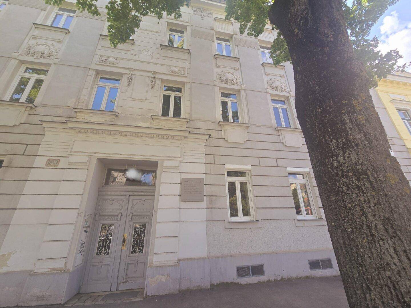 Historische Fassade eines Altbaus mit verzierten Fenstern und Eingangsbereich.