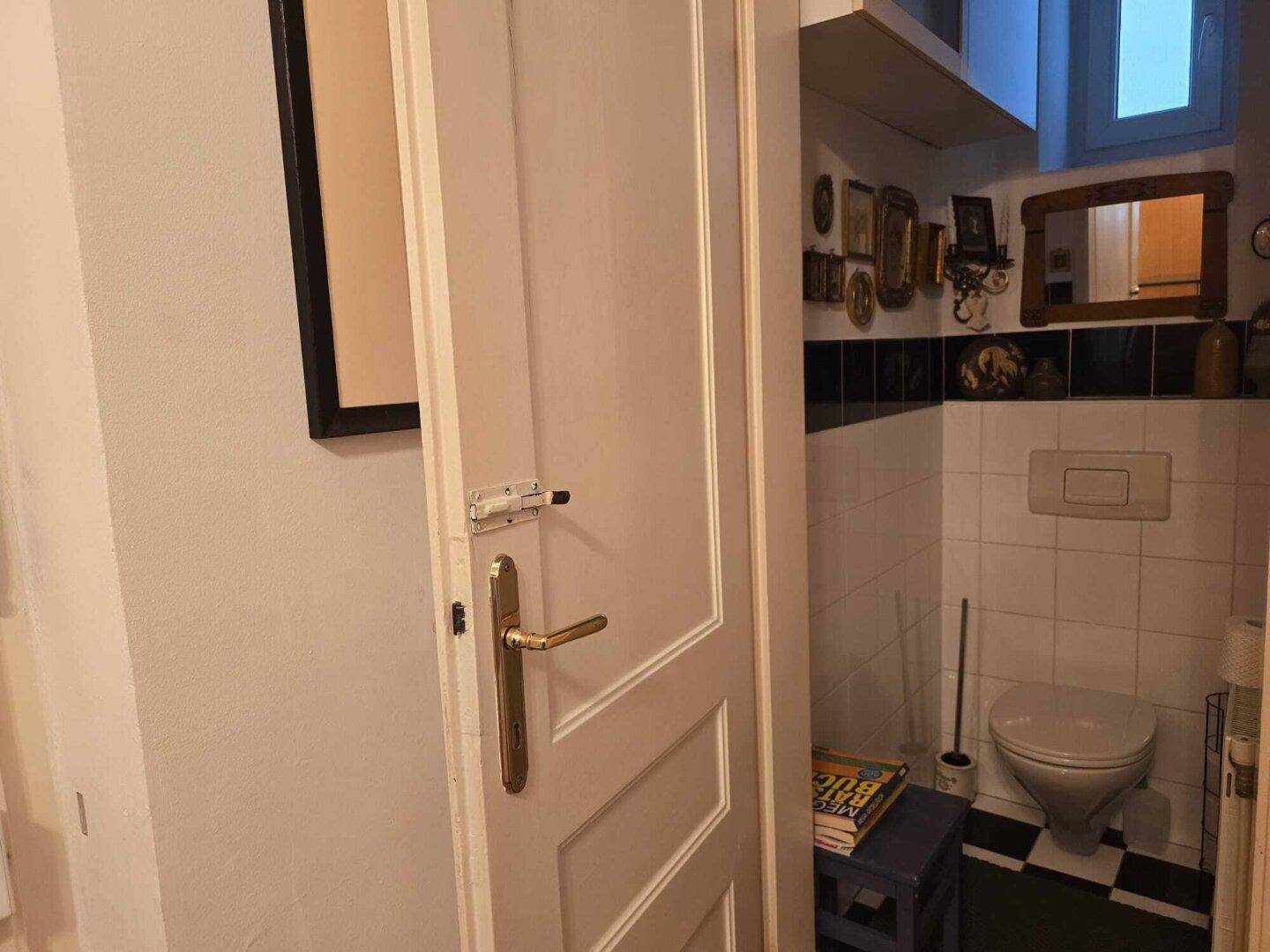 Kleines Gäste-WC mit weiß-schwarzen Fliesen und einfacher Ausstattung.