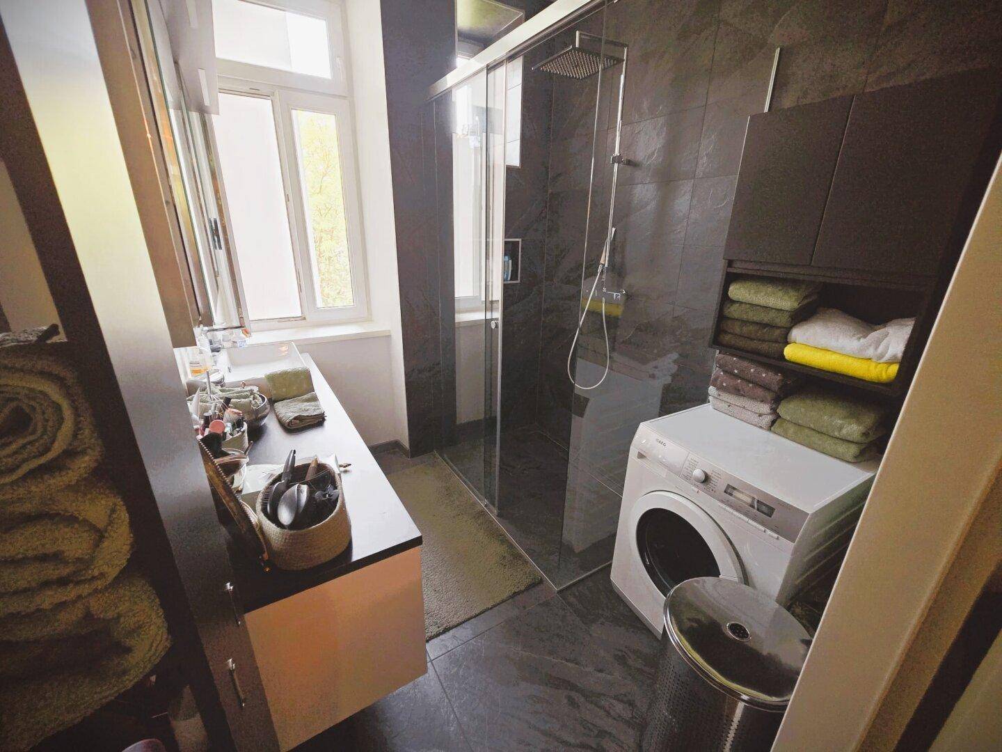 Modernes Badezimmer mit ebenerdiger Dusche, Waschmaschine und Fenster für Tageslicht.