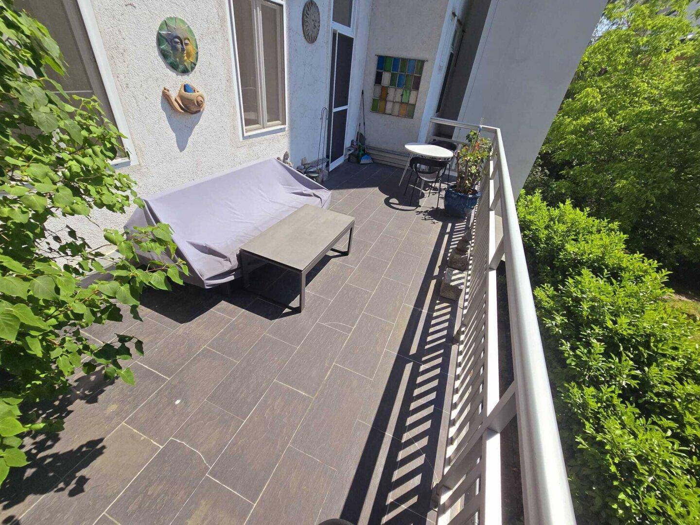 Sonnige Terrasse mit Außenmöbeln und Blick auf die umliegende grüne Landschaft.