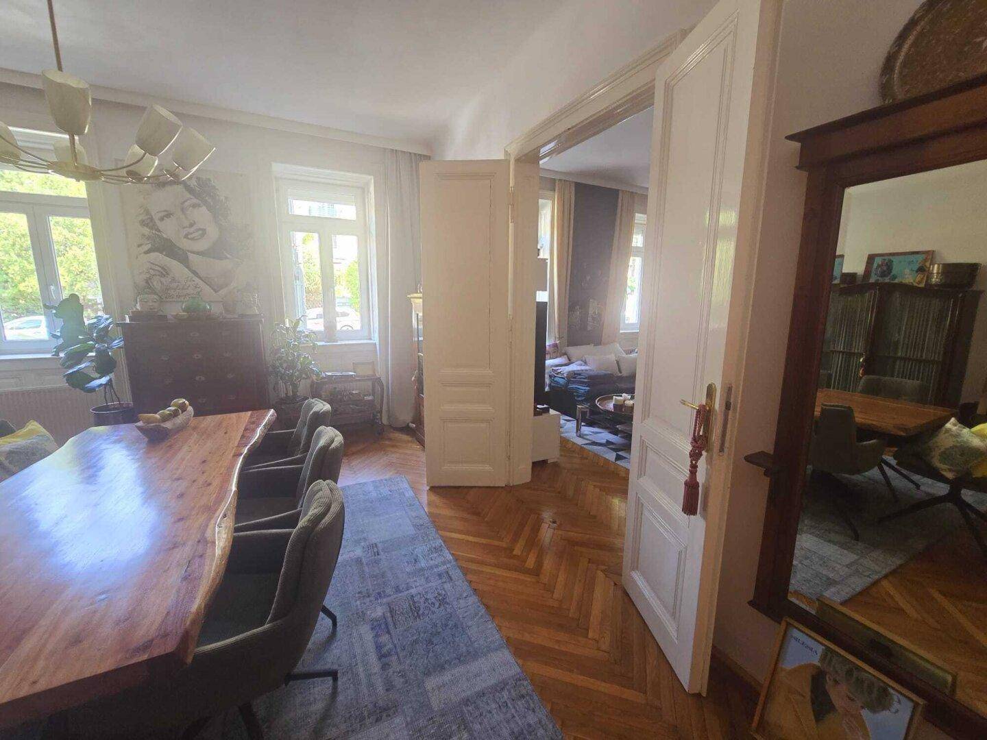 Offener Wohn- und Essbereich mit Fischgrätparkett und Verbindungstür zum Wohnzimmer.