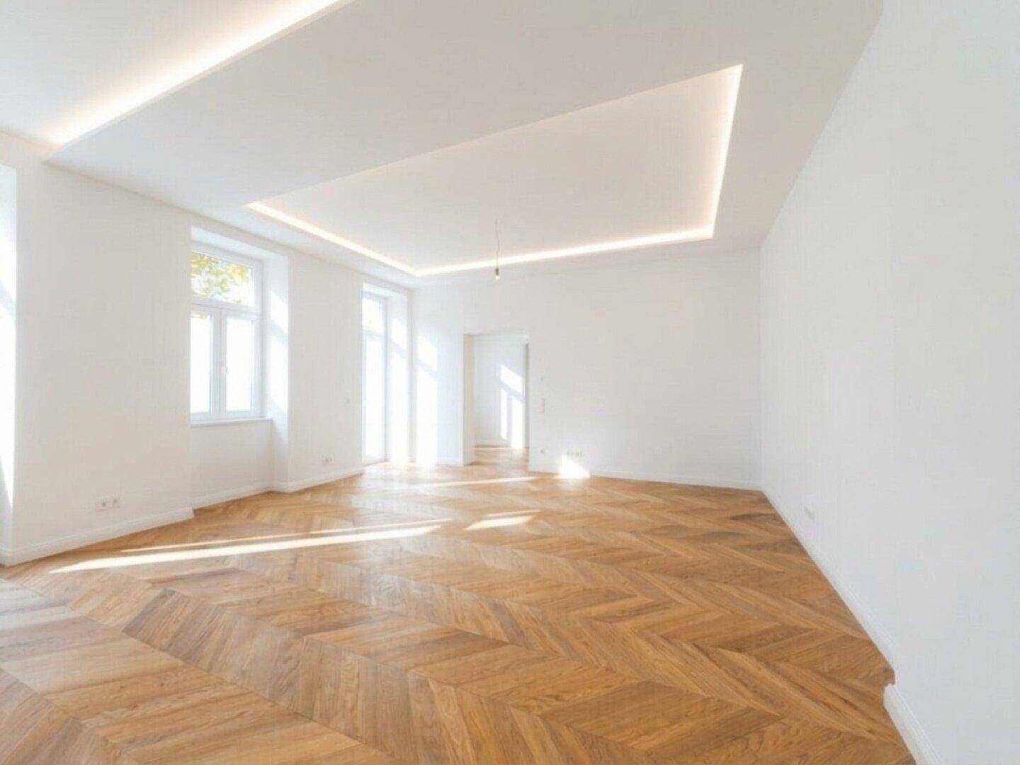 Lichtdurchfluteter Raum mit elegantem Fischgrätparkett und moderner Deckenbeleuchtung, bietet viel Platz.