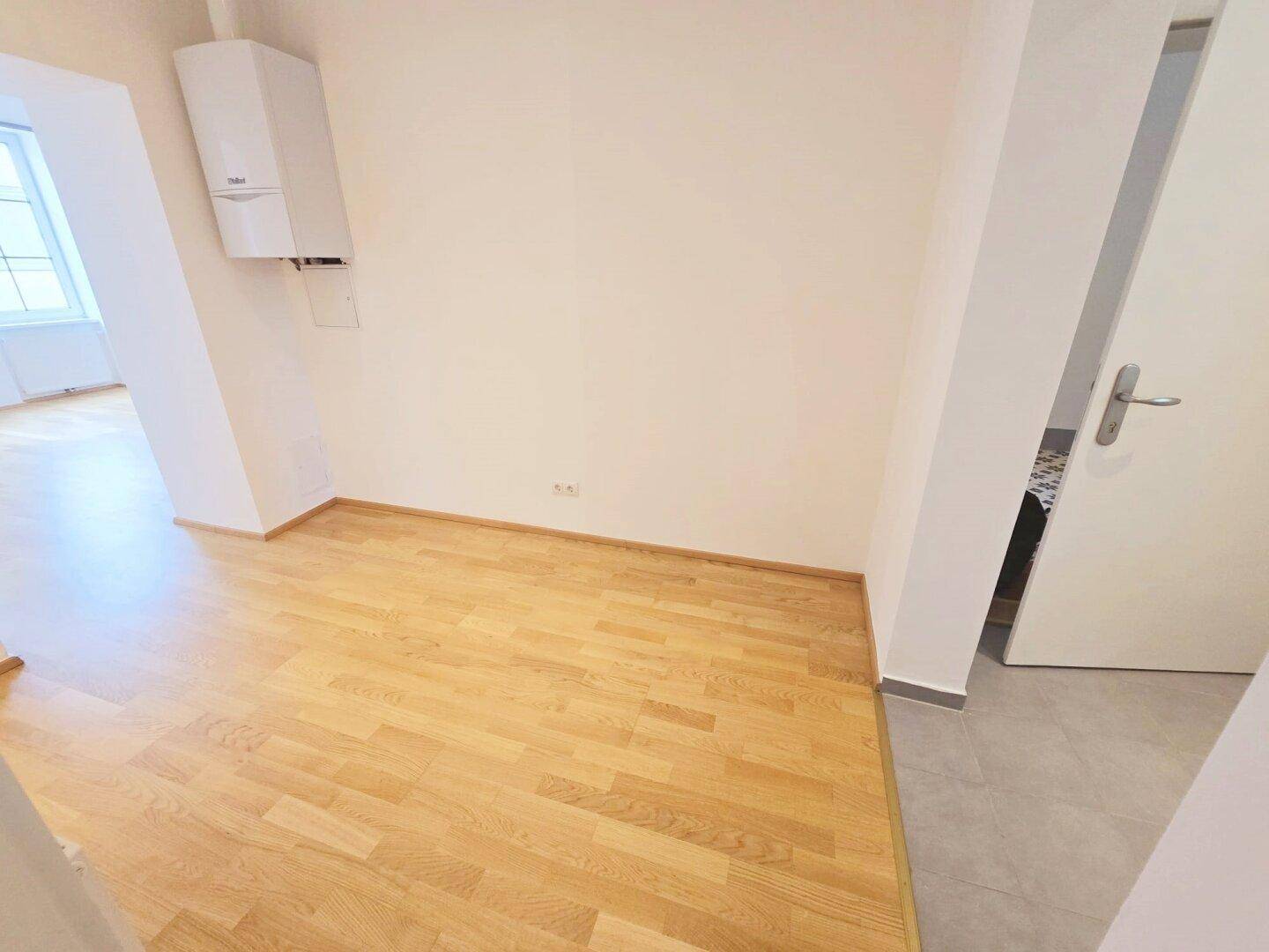 Ecke eines Zimmers mit Parkettboden und einem an der Wand montierten Heizkessel.