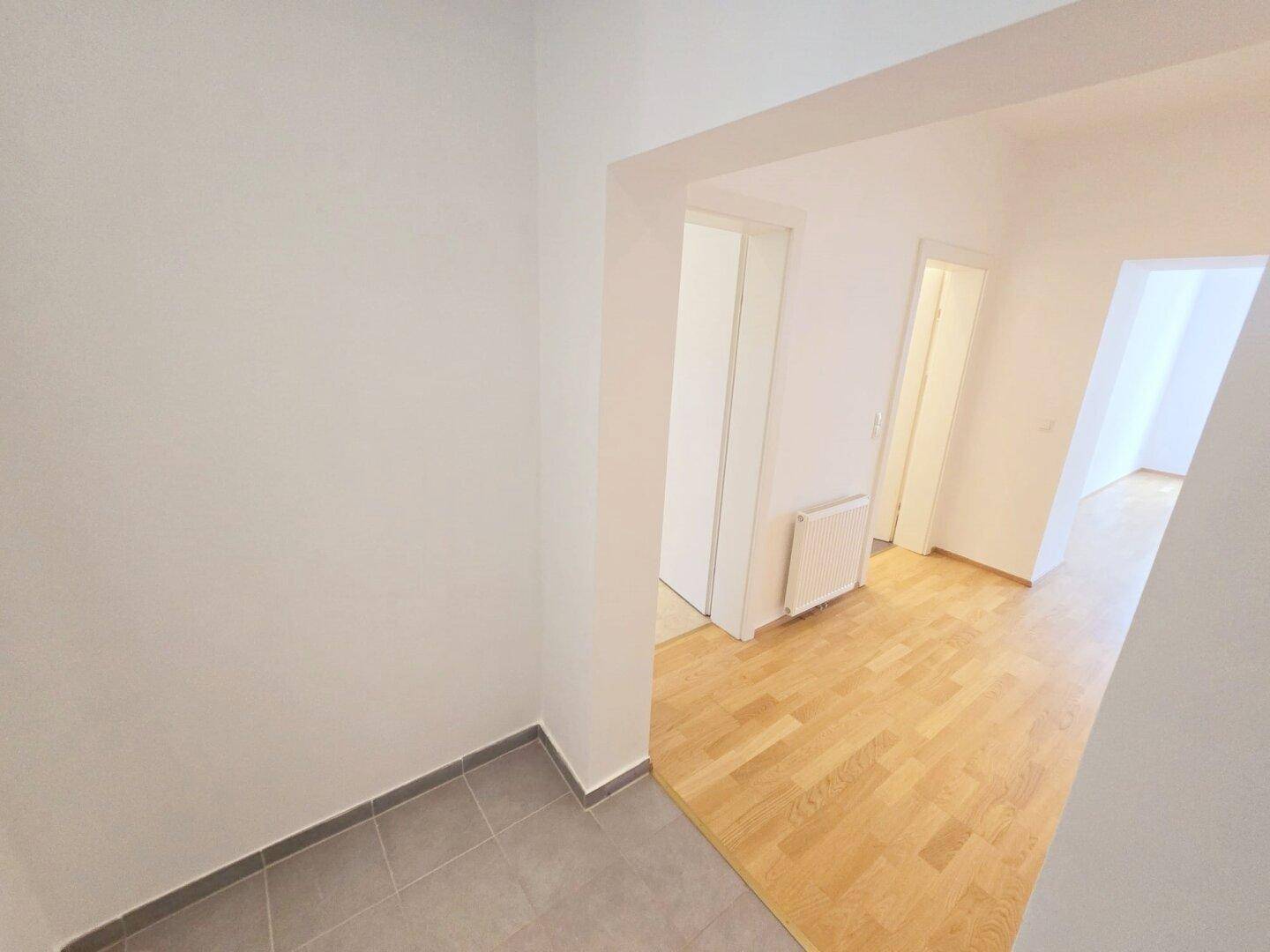 Geräumiger Flur mit Übergang von Parkett- zu Fliesenboden, verbindet verschiedene Räume.
