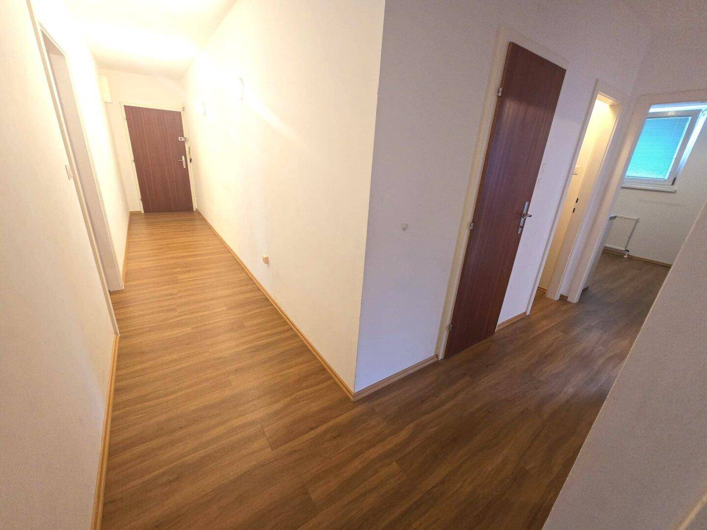 Heller Flur mit Laminatboden und Zugang zu verschiedenen Zimmern der Wohnung.