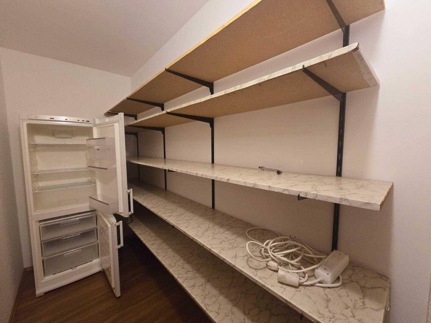 Praktischer Abstellraum mit Regalen und einem Kühlschrank, bietet viel Stauraum.