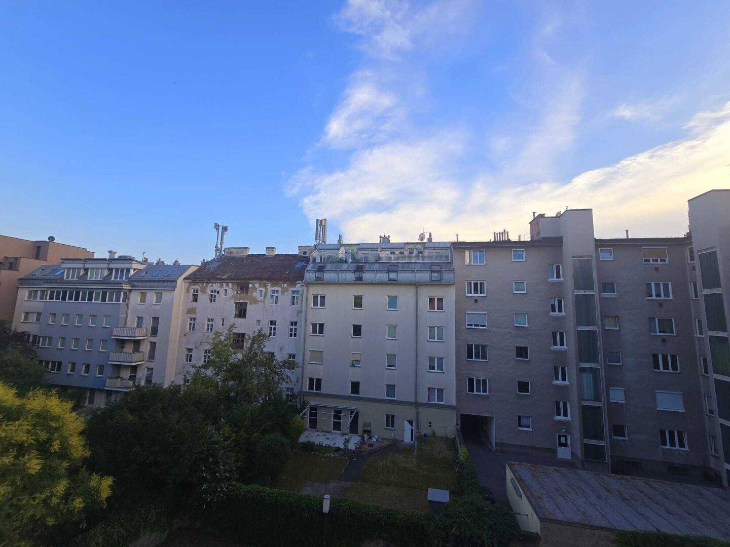 Außenansicht von Wohngebäuden mit einem Innenhof unter blauem Himmel.