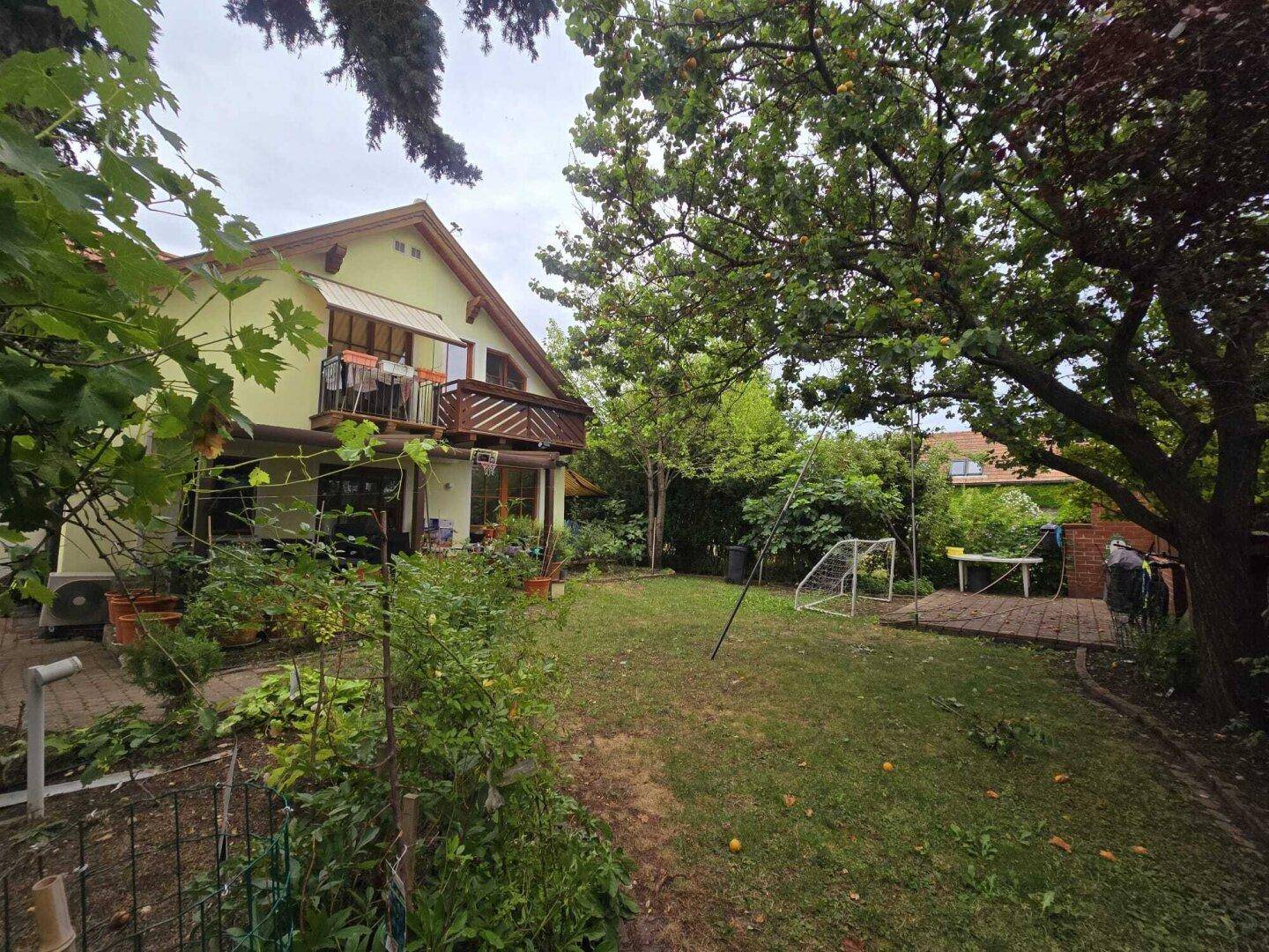 Ruhiger Hinterhof mit Rasen, üppiger Vegetation und einem Balkon am Haus.