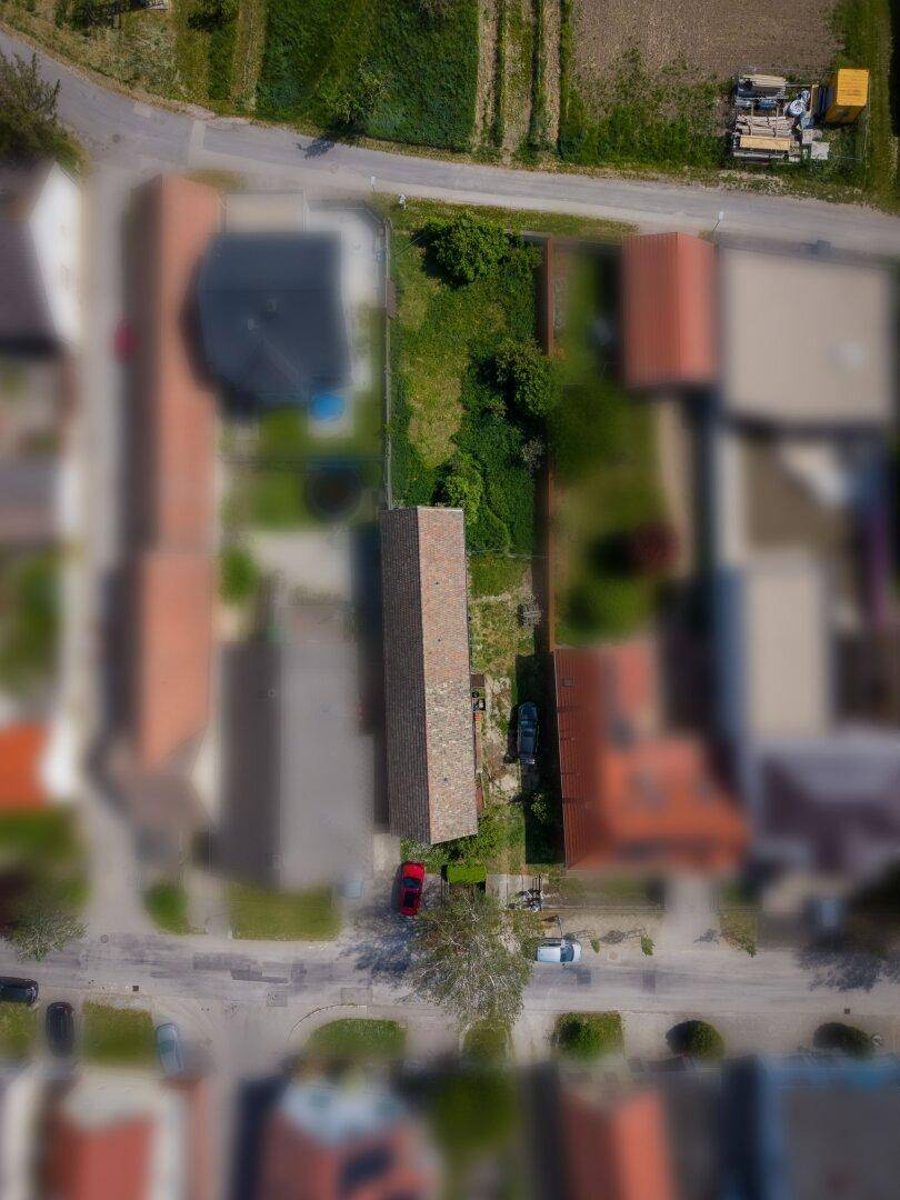 Übersicht aus der Luft des Grundstücks mit langem Gebäude und der umliegenden ländlichen Bebauung.