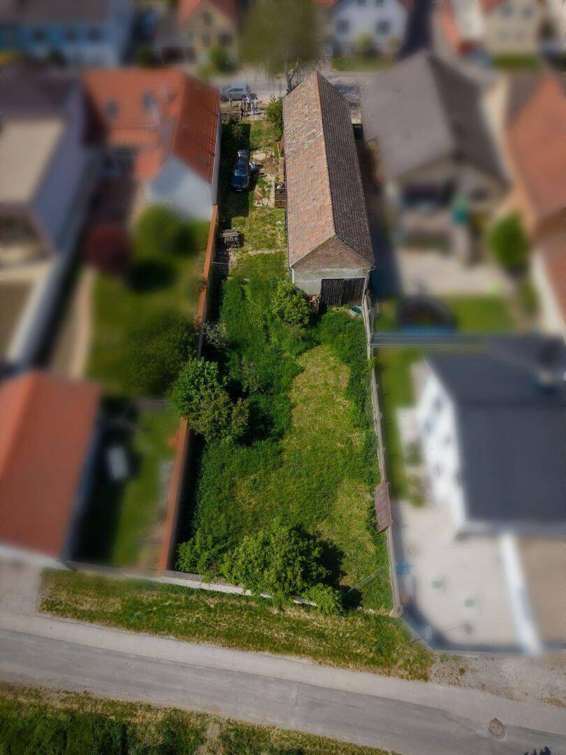 Vogelperspektive des langgestreckten Grundstücks mit Gebäude und angrenzenden Wohnhäusern.