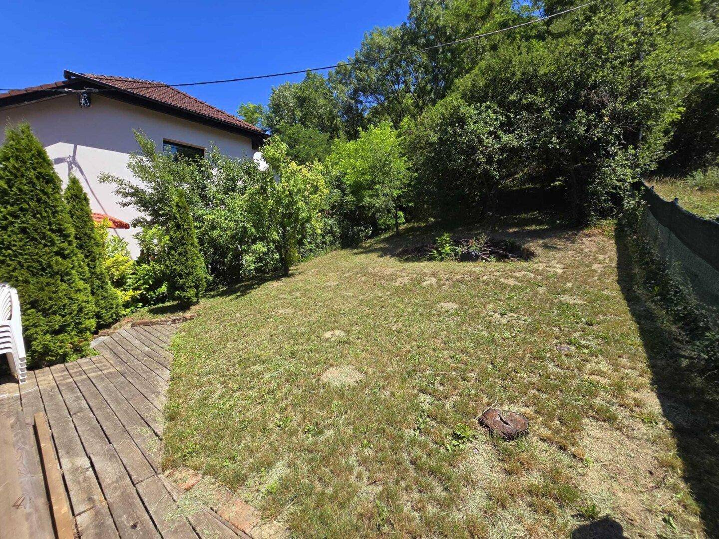 Sonniger Gartenbereich mit Holzterrasse und viel Grün.