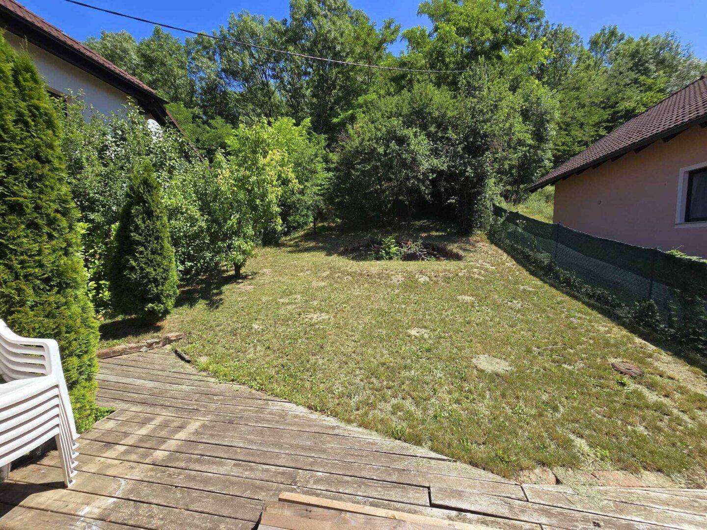 Sonniger Gartenbereich mit Holzterrasse und viel Grün.