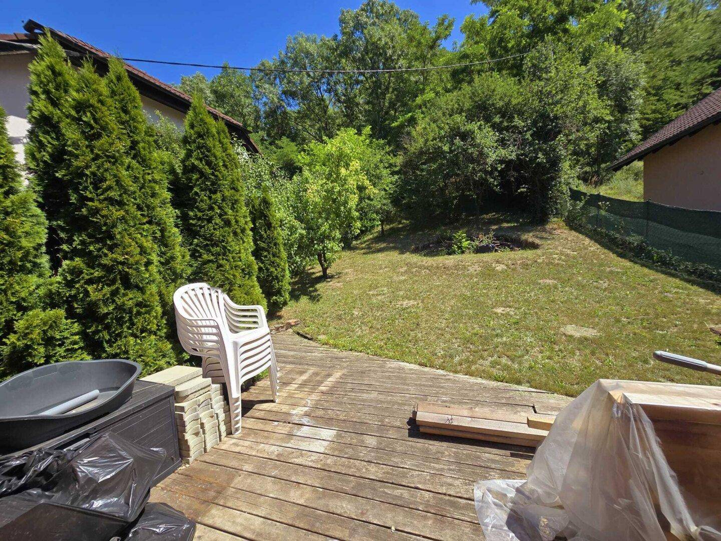 Sonniger Gartenbereich mit Holzterrasse und viel Grün.