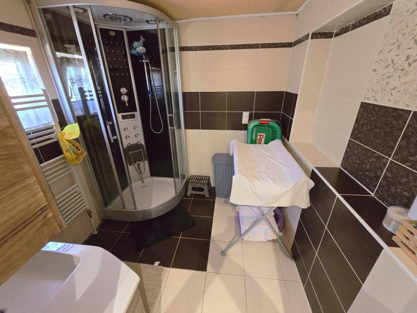 Badezimmer mit moderner Duschkabine, Fliesenwänden und Heizkörper.