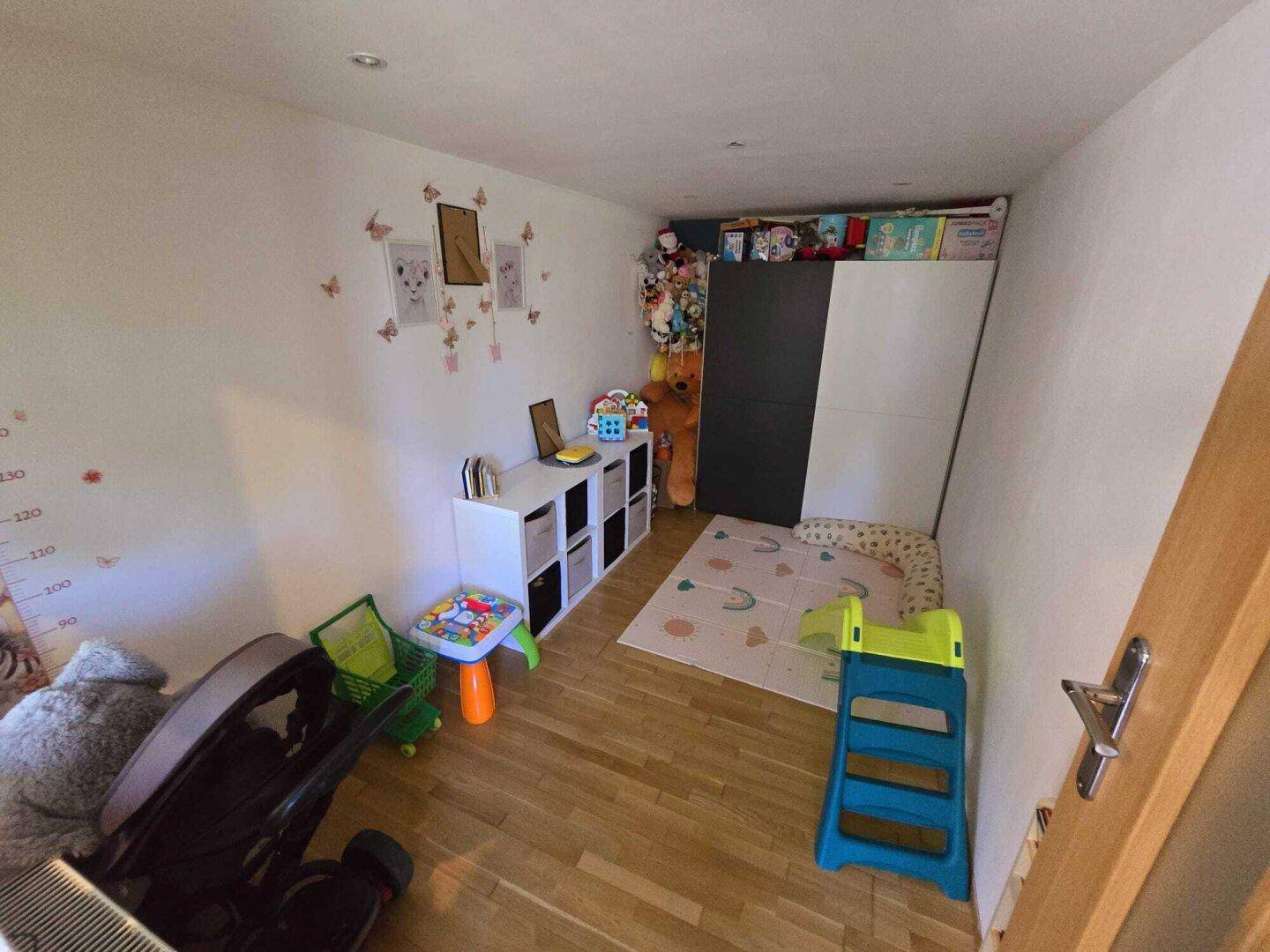 Kinderzimmer mit Laminatboden, Spielzeug und kindgerechter Dekoration.