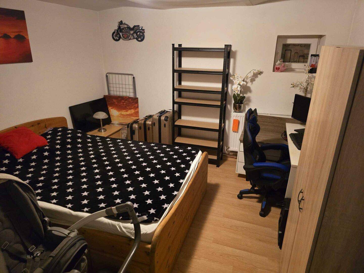 Schlafzimmer mit Holzbett, Schreibtisch und Sternenmuster-Bettwäsche.