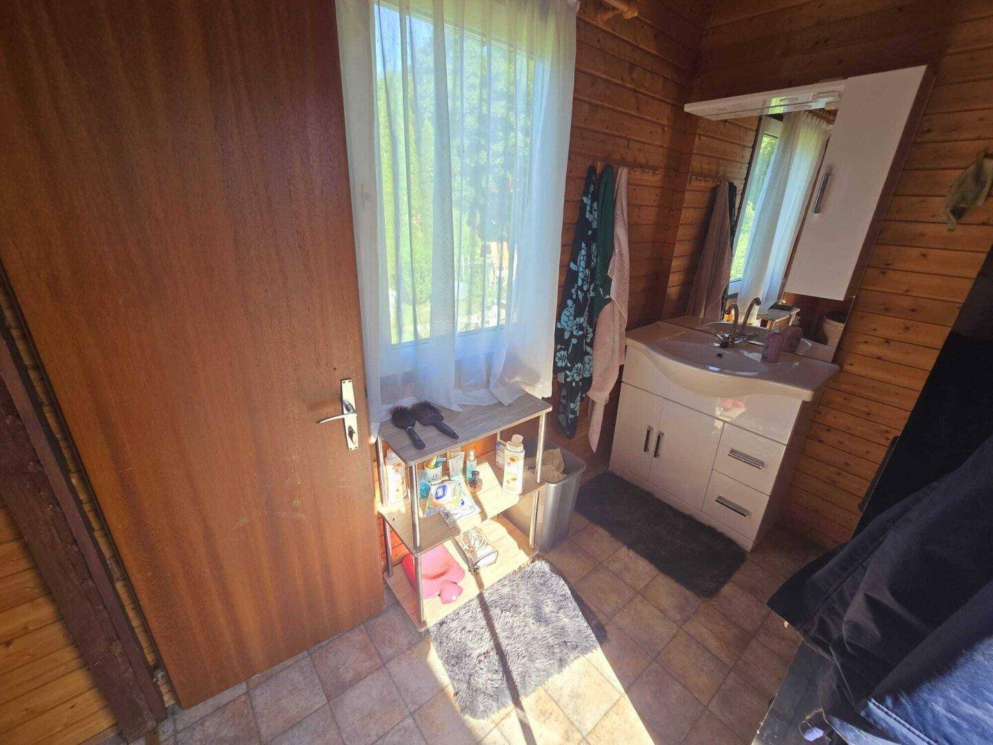 Kleines Badezimmer mit Holzvertäfelung, einem Waschbecken und einem Fenster.