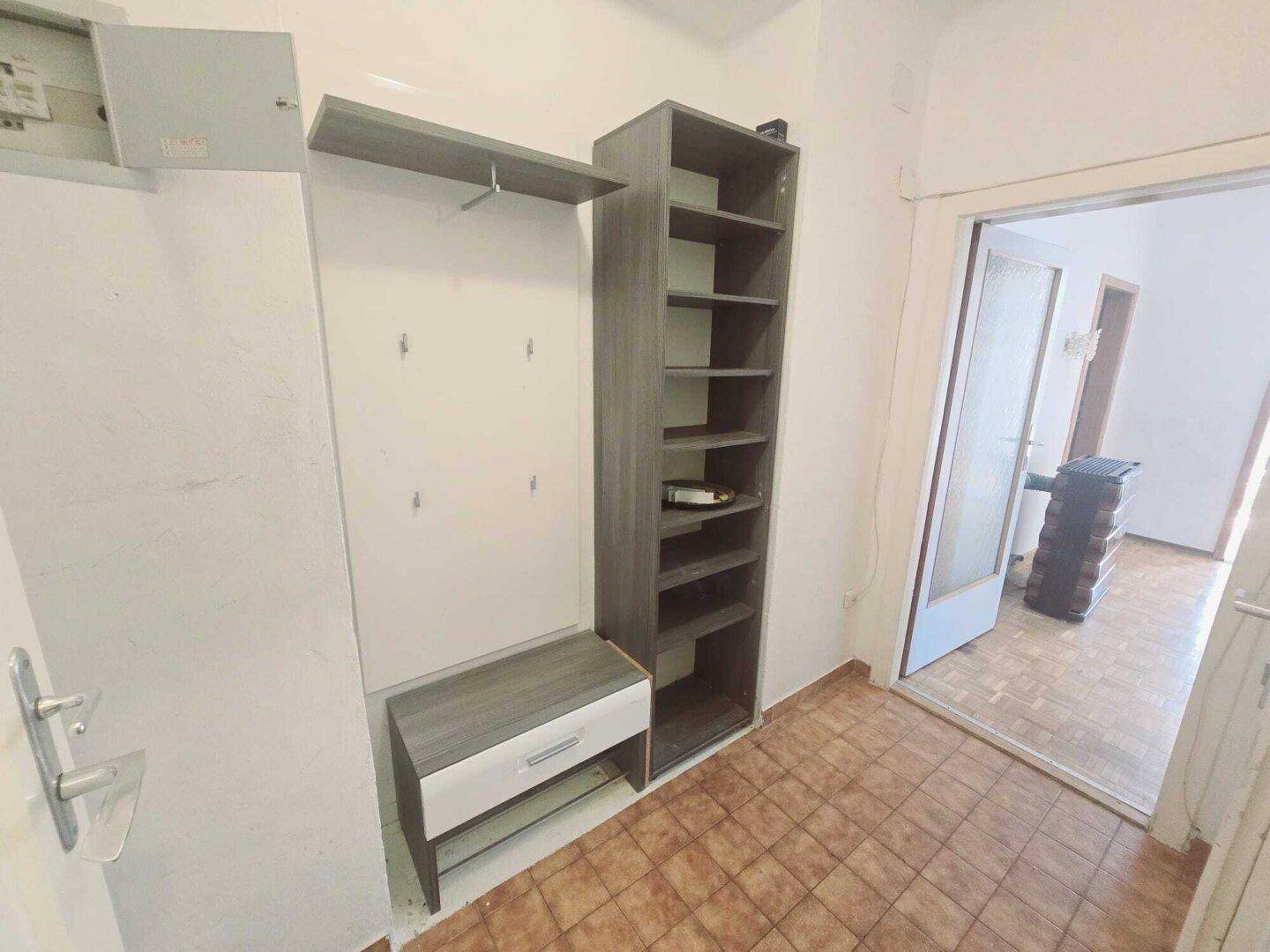 Funktionaler Flur mit Fliesenboden und praktischen Regalsystemen für Stauraum.