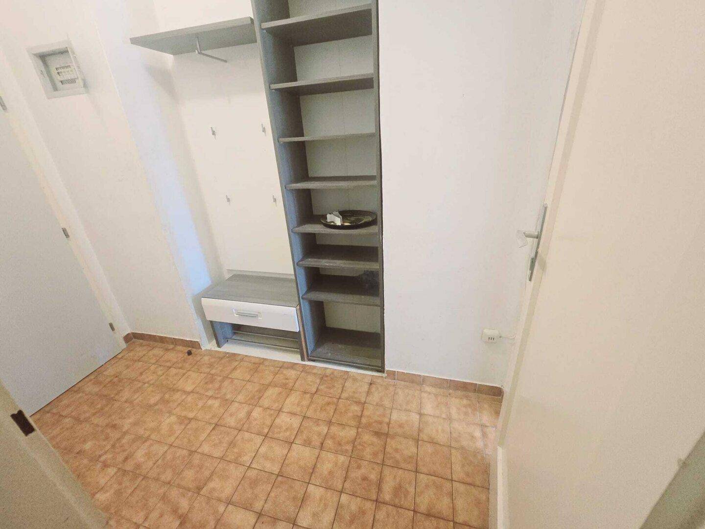 Funktionaler Flur mit Fliesenboden und praktischen Regalsystemen für Stauraum.