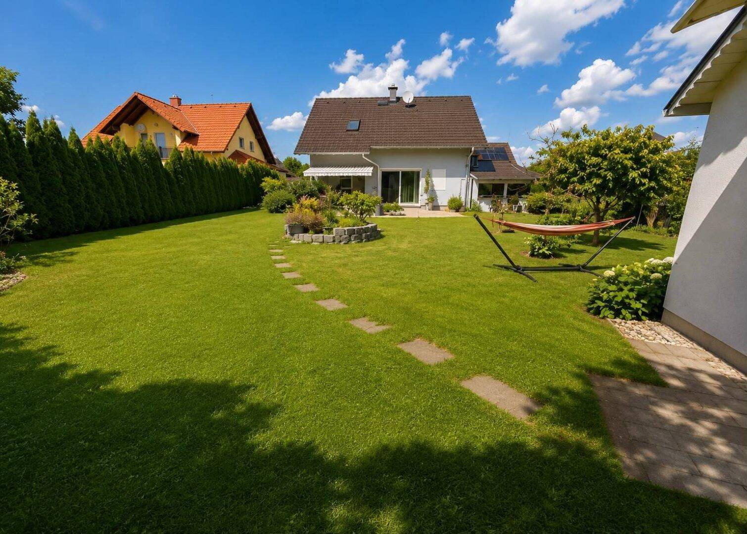 Weitläufiger grüner Garten mit Hängematte und gepflegter Hecke, perfekt zum Entspannen.