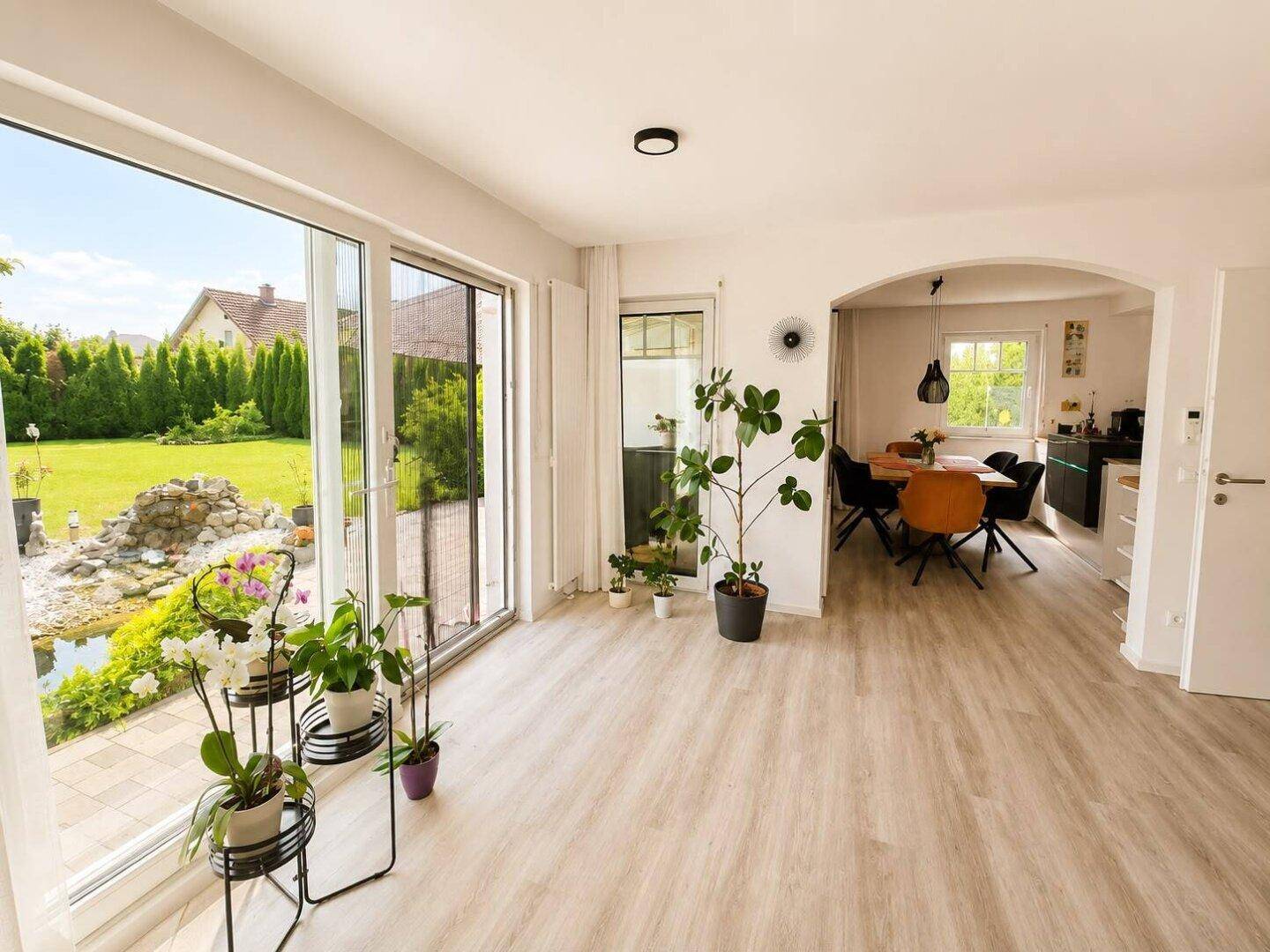 Helles Wohnzimmer mit großen Schiebetüren zum Garten und Blick auf den Teich.