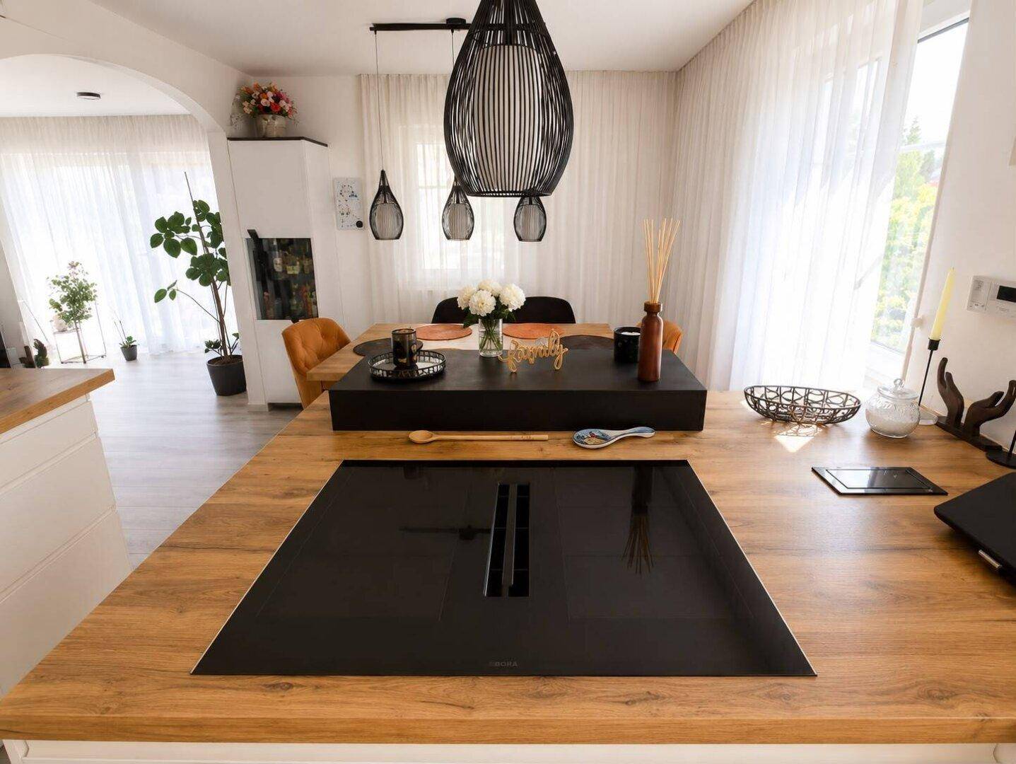 Moderne Kücheninsel mit integriertem Induktionskochfeld und Holz-Arbeitsplatte.