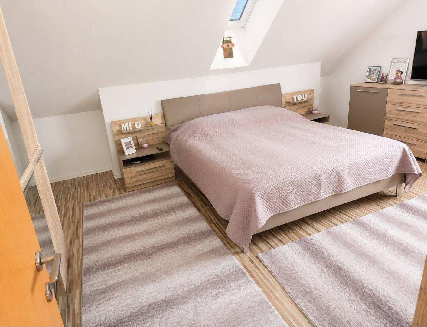 Gemütliches Schlafzimmer im Dachgeschoss mit schrägen Wänden und Dachfenster.
