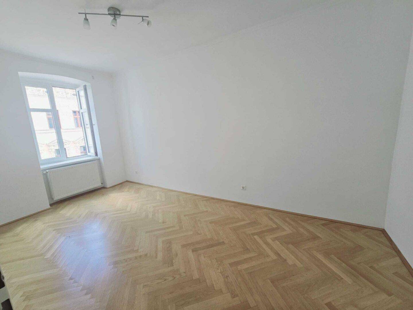 Helles Schlafzimmer mit weiß gestrichenen Wänden und elegantem Fischgrätparkett.