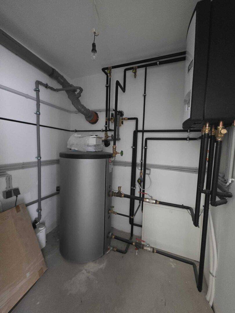 Technikraum mit Heizungsanlage und Warmwasserspeicher, ordentlich installiert.