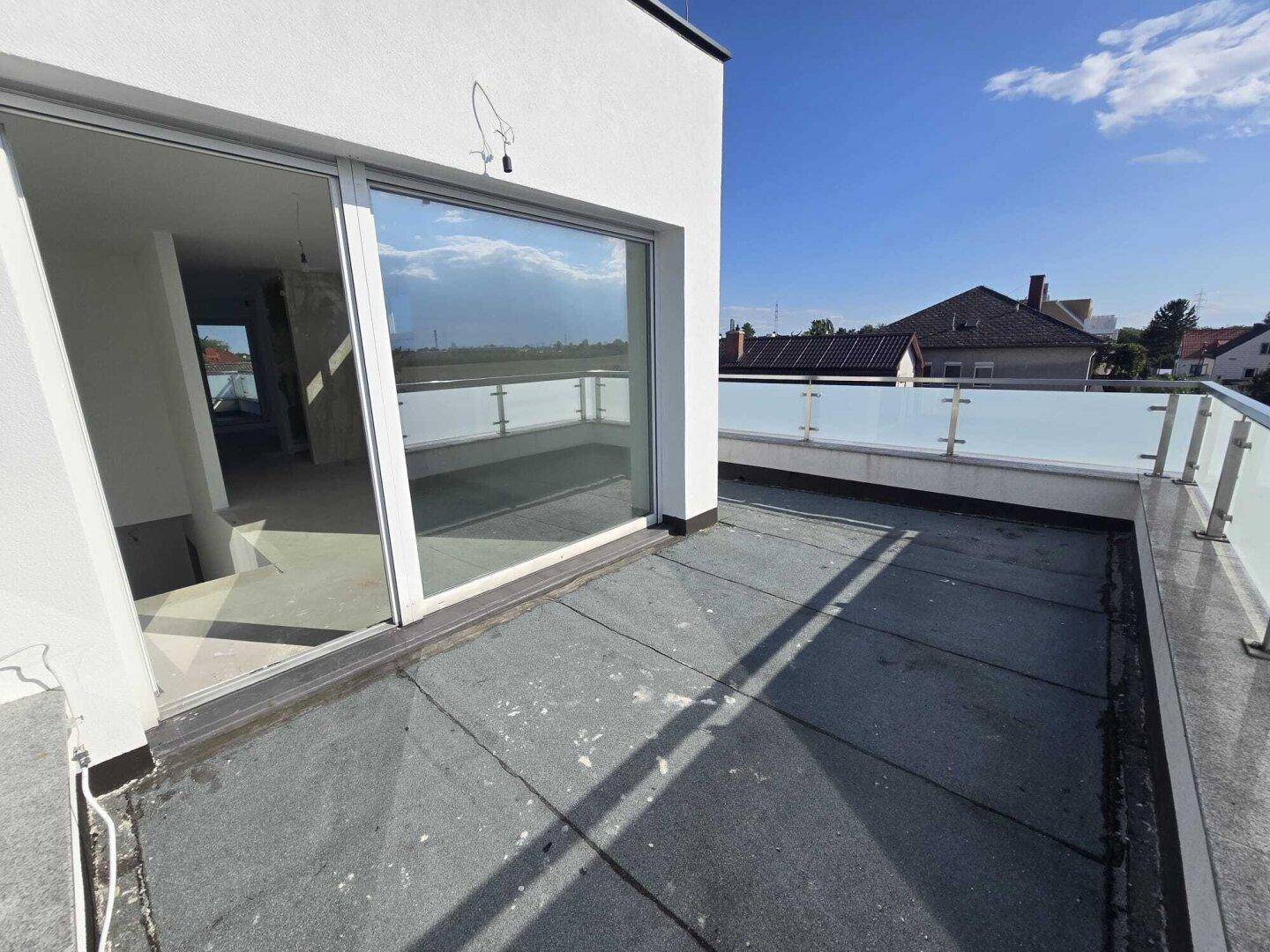Dachterrasse mit Glasgeländer und Blick auf die Umgebung, noch im Bau.